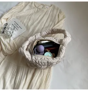 Vue macro d'un sac nuage matelassé blanc crème montrant l'intérieur spacieux et les essentiels