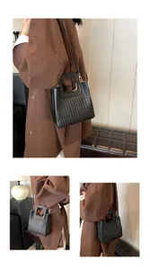 Détail du sac seau noir tissé avec une poignée carrée unique et une texture en cuir