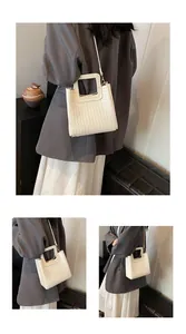 Détail du sac seau tressé crème avec poignée découpée et texture en cuir synthétique
