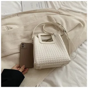 Détail du sac seau tissé crème avec poignée carrée évidée et bandoulière réglable