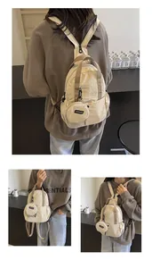 Détail d'un sac à dos en nylon froissé crème avec un petit porte-monnaie rond attaché