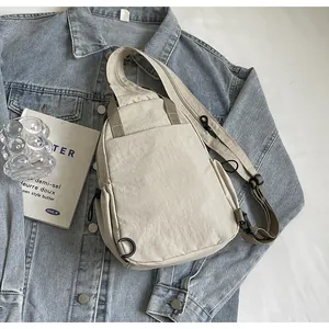 Détail du sac bandoulière minimaliste en nylon beige avec sangle réglable sur denim