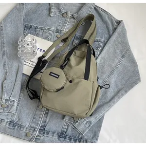 Détail du sac de poitrine en nylon vert sauge avec petite pochette ronde et logo