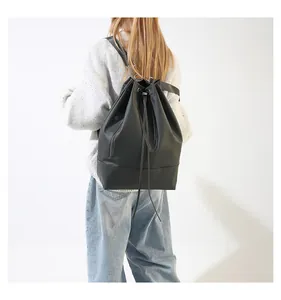 Detailansicht eines schwarzen Kordelzug-Rucksacks mit mattem Kunstleder und Reißverschlusstasche