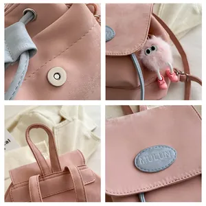 Detail of pink fashion backpack showing magnetic buckle, blue drawstring, and plush charm