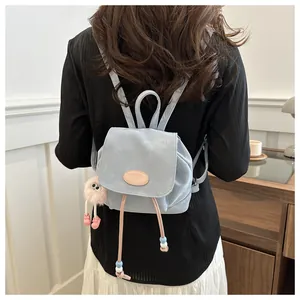 Detail of light blue mini backpack with plush pendant and adjustable straps on model