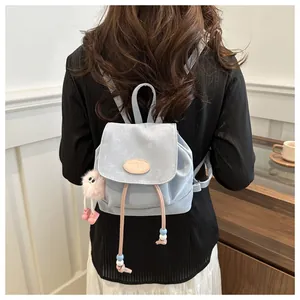 Back view of a mini light blue suede backpack with a pink plush charm and drawstring
