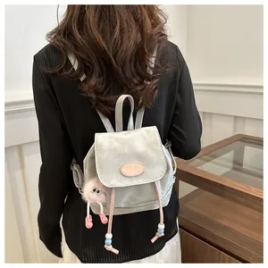 Detail of silver-grey mini backpack with texture and cute pink plush monster charm