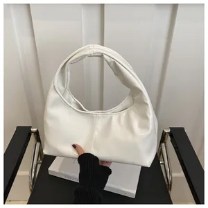 Détail du sac à main blanc brillant en cuir verni avec coutures et poignée incurvée