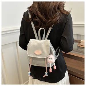 Silver metallic mini backpack with pink plush charm and beaded drawstring on female model