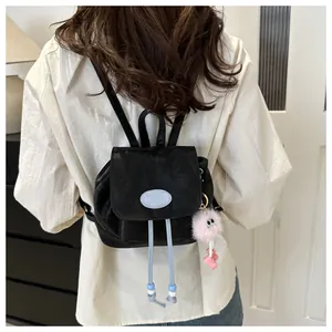 Close-up of black leather mini backpack with drawstring and pink plush charm