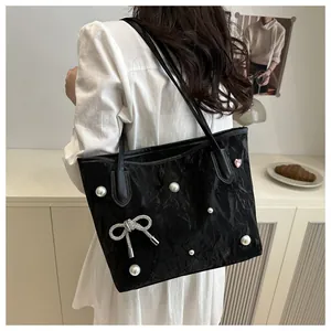 Detail of black pleated tote bag with pearls, silver bow pendant and pink heart pin