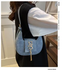 Détail du sac croissant bleu clair avec boucle en S dorée et pampille métallique chic