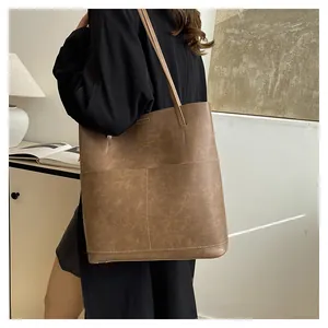 Brown vintage faux leather tote bag with large capacity pocket shown on shoulder