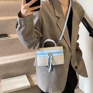 Beige canvas en lichtblauw lederen mini box tas met kwastjes gedragen op een trap