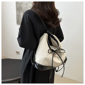 Detail of contrast stitching on black leather strap of this beige canvas tote bag