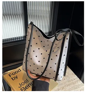 Détail du sac seau blanc à pois avec un nœud décoratif en ruban noir élégant