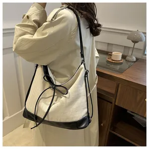 Detail of canvas tote with black faux leather trim and ribbon bow on model
