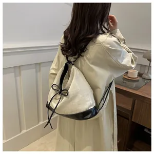 Detail of canvas backpack featuring black leather trim and decorative bow drawstring