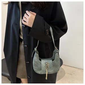 Vue détaillée du logo en métal doré et du gland métallique sur le sac demi-lune