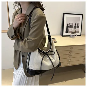 Detail of canvas tote bag with black leather trim and decorative bow accent