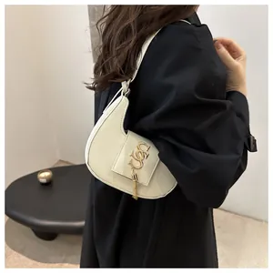 Détail du sac croissant blanc montrant l'ornement logo doré et l'accessoire à pampilles