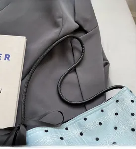 Détail du sac à pois bleu clair avec anses en corde noire et superposition en dentelle