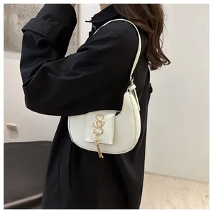 Détail du sac demi-lune blanc avec logo métallique doré et pendentif à franges élégant