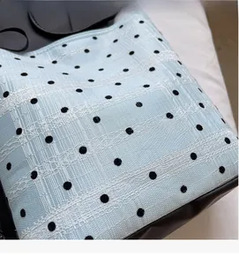 Détail du tissu en dentelle bleu clair à pois noirs et à la texture douce