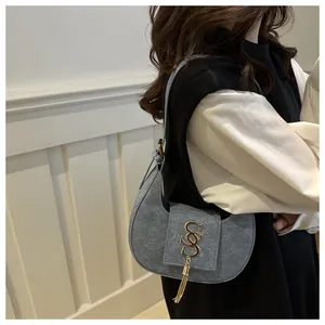 Détail du sac croissant en texture denim avec boucle dorée et pendentif à glands