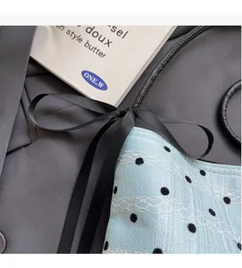Détail du sac seau bleu clair avec pois noirs et revêtement en dentelle blanche