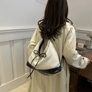 Large canvas tote backpack with black leather trim and bow detail for women in 2024 fashion