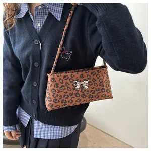 Detail view of leopard print underarm bag featuring a metallic silver bow ornament