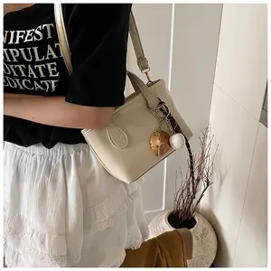 Detail of cream-colored tote bag featuring baseball charm and FASHION lettering