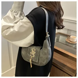Détail du sac croissant gris avec logo S doré et gland métallique porté par un modèle
