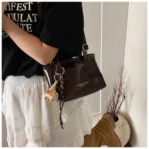 Detail of dark brown glossy leather tote bag with baseball charm and letter print