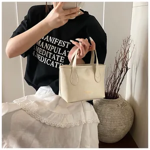 Detail of the cream PU leather tote bag with elegant top handles and golden text detail