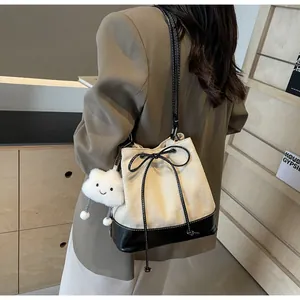 Detail of canvas bucket bag with black leather trim and cute plush cloud pendant