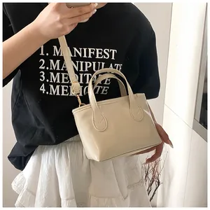 Detail of cream white glossy PU leather handbag with cylindrical handles and metal buckle