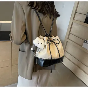 Detail of canvas drawstring bucket bag featuring black leather base and cloud charm