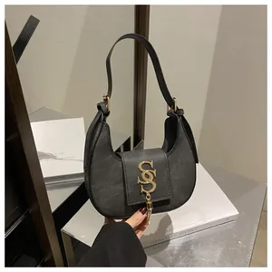 Détail d'un sac demi-lune en cuir noir avec logo métallique doré et gland décoratif