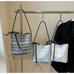 Détail de trois sacs seaux minimalistes à pois avec de fines bandoulières ornées de nœuds