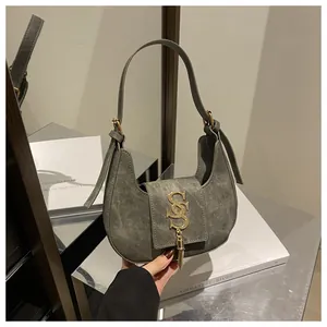 Détail du sac croissant en daim gris avec logo SS doré et pampilles métalliques