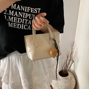 Fashionable cream mini tote bag with glossy finish and strawberry charm accessory