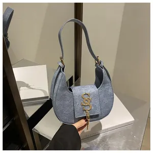 Détail du sac croissant bleu clair avec logo doré et pendentif à pampilles