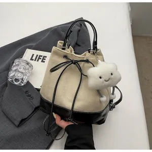 Close-up of contrast canvas bucket bag with drawstring closure and plush cloud charm