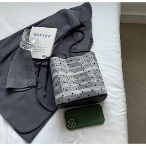 Détail du sac seau en toile à pois avec nœud et base en cuir sur un blazer gris