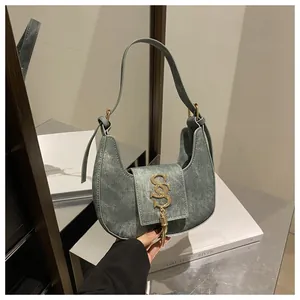Détail du sac selle rétro en croissant avec logo en métal doré et gland à franges