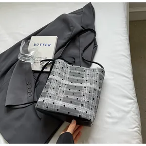 Détail du sac seau à carreaux avec pois noirs, nœud en satin et bandoulière en cuir