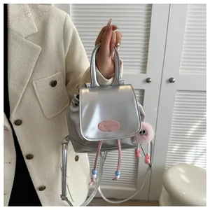 Detail of silver mini backpack with pink drawstring and cute monster plush pendant